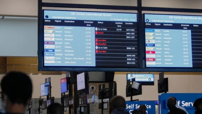 مسافرين في أحد مطارات جنوب إفريقيا يتابعون رحلاتهم بعد إلغاء بعضها من جانب عدة دول