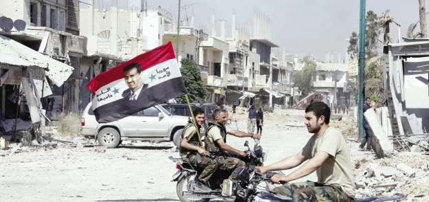 جنود سوريون يحملون العلم السورى مزيناً بصورة «بشار»