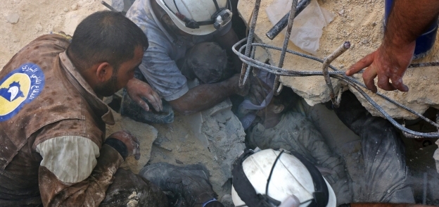 الدفاع المدنى يحاول إخراج أحد ضحايا القصف على حلب من تحت الأنقاض «أ.ف.ب»