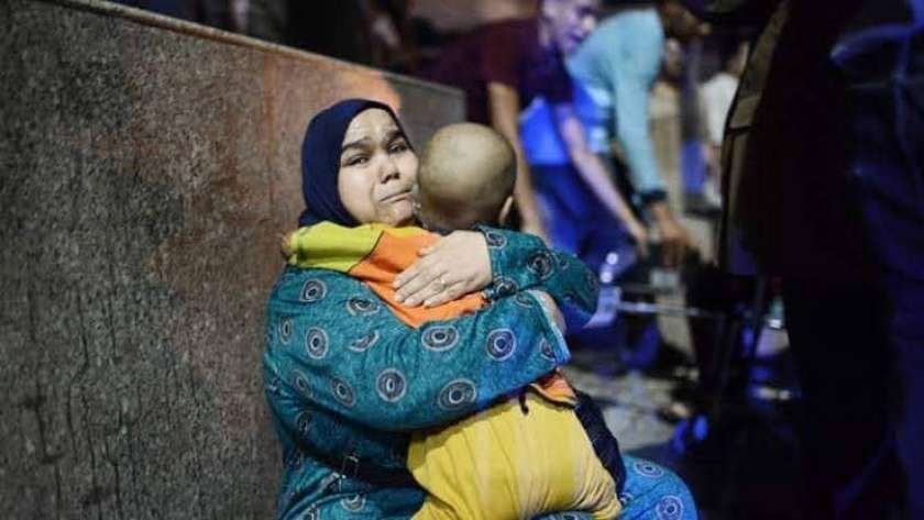 فايزة تحمل ابنها عبدالرحمن أمام معهد الأورام