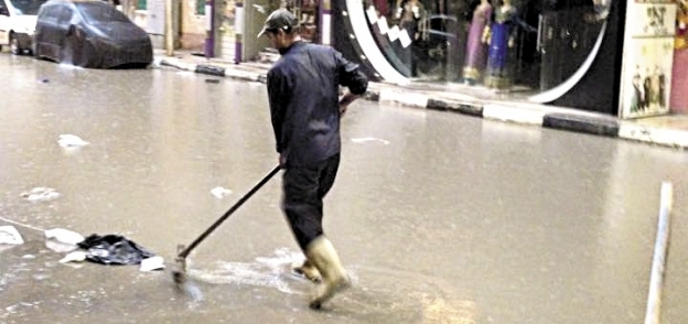 عبدالسلام الشاذلى عامل نظافة يؤدى عمله وسط الأمطار