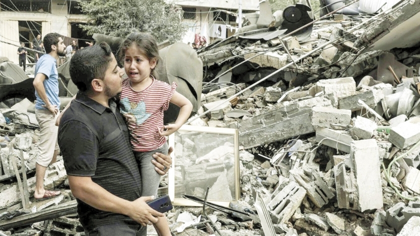 فلسطينى وابنته يبكيان بجوار منزلهما المنهار جراء الغارات الإسرائيلية