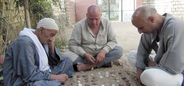 ثلاثة رجال يلعبون سيجا بعد انتهائهم من العمل فى الأرض