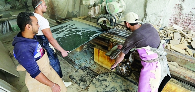 بعض العمال أثناء قطع لوح رخام