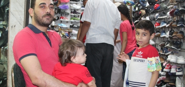 أب يحاول شراء ملابس العيد لأطفاله بأسعار مقبولة