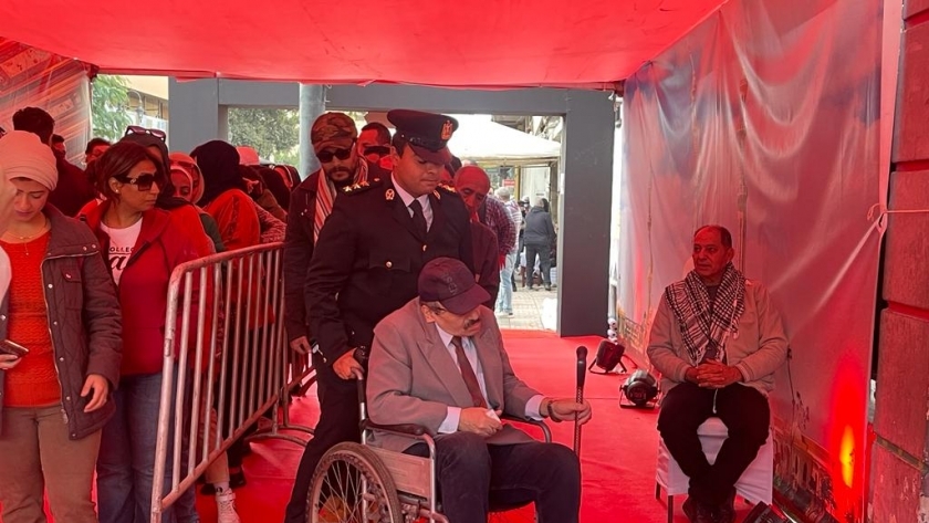 ضابط شرطة يساعد أحد كبار السن على الإدلاء بصوته في انتخابات الرئاسة