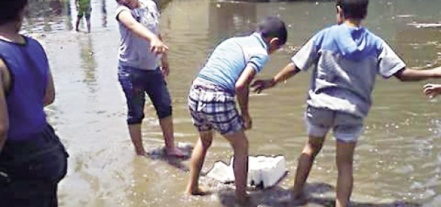 أطفال قرية «بنى مراس» يلعبون فى مياه الصرف