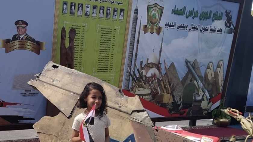 طفلة تلتقط صورة تذكارية بجانب حطام الطائرة فانتوم الإسرائيلية
