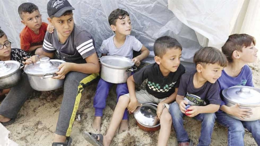 أطفال ينتظرون وجبات الطعام في المخيمات