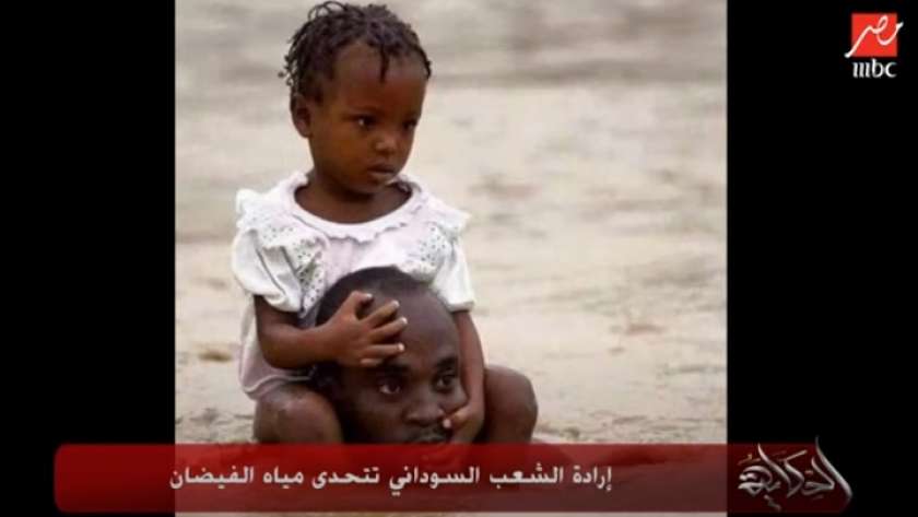 رجل سوداني يحمل ابنته حتى لا تغرق في مياه الفيضانات