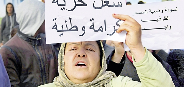 سيدة تونسية ترفع لافتة تجسد مطالب المتظاهرين