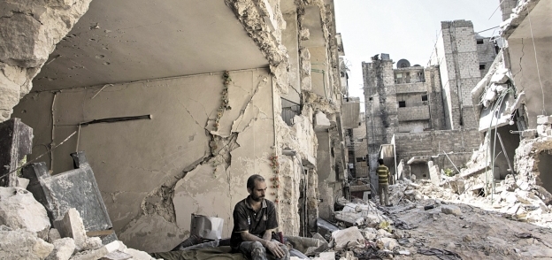 سورى يجلس أمام حطام منزله فى مدينة حلب «أ.ف.ب»