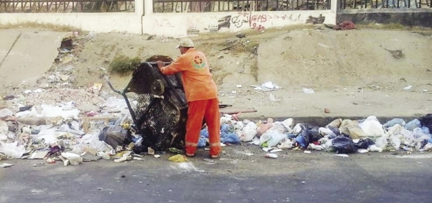 عامل النظافة يلقى القمامة فى الشارع
