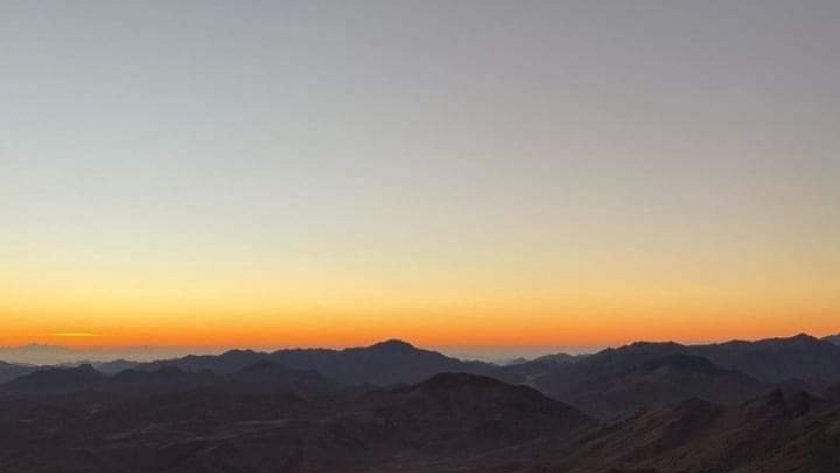 سياح يشاهدون شروق الشمس من فوق قمة جبل موسى