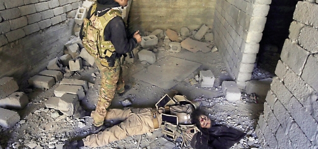 جندى عراقى بجوار جثة داعشى بعد تصفيته «أ.ف.ب»