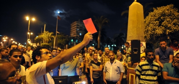 مواطن يرفع بطاقة حمراء أثناء سماع خطاب «مرسى» الأخير