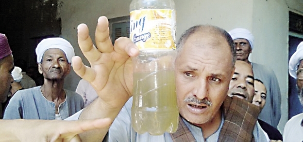 مواطن يحمل مياهاً ملوثة أمام محطة التنقية فى «أبوتشت»