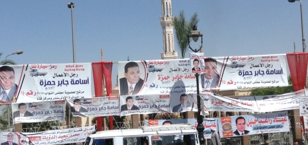 بالصور | مرشحو قنا يعلقون لافتاتهم على سور "القناوي": دعاية وبركة