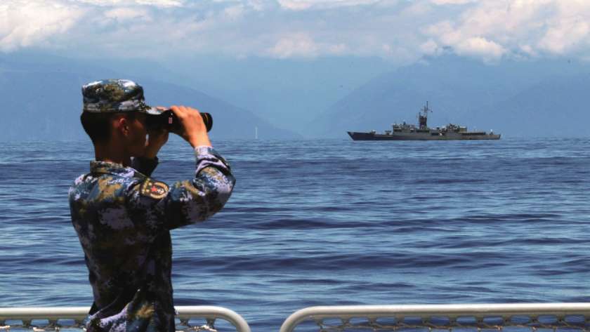 جندي صيني يراقب إحدى السفن في مضيق تايوان