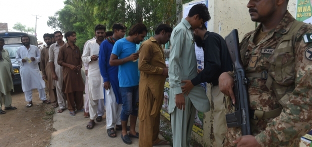 شرطي باكستاني يفتش الناخبين خارج مركز اقتراع في لاهور صباح اليوم