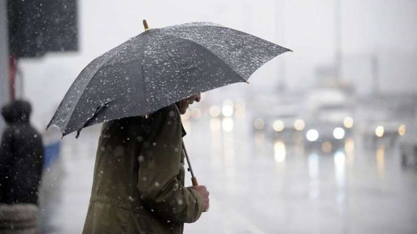 مواطن يحتمي بمظلة من الأمطار  - أرشيفية