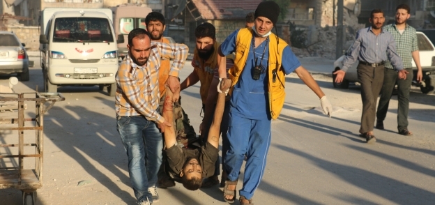 سوريون يحملون قتيلاً نتيجة القصف على منازل بحى صلاح الدين «أ . ف. ب»