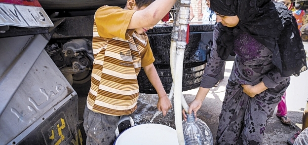 أحد الأطفال يستخدم «جركن» لملء المياه