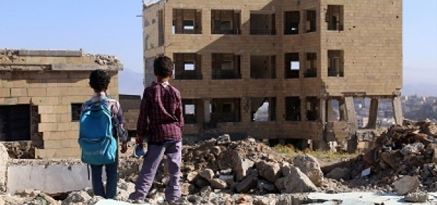 أطفال بنظرون إلى أطلال مدرستهم بعد تدميرها بسبب الحرب في اليمن