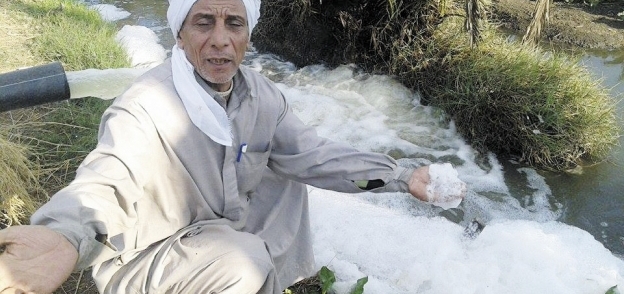 أحد مزارعى القرية يشير إلى مخلفات مياه الرى