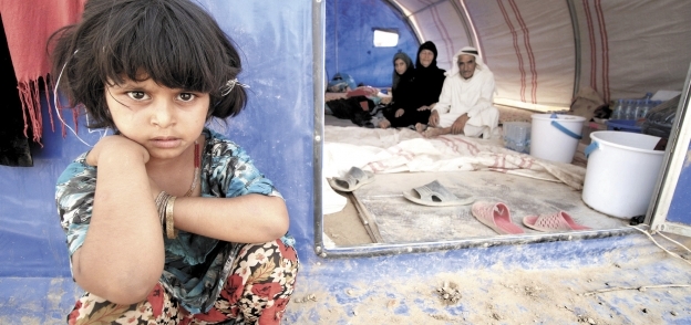 طفلة مع أسرتها داخل أحد مخيمات الفارين من الفلوجة بالعراق «أ.ف.ب»