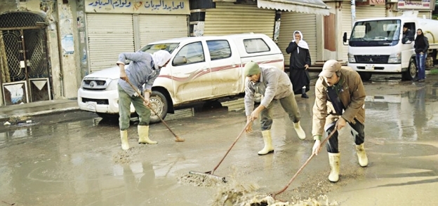 العمال أثناء عملية كسح مياه الأمطار بـ«مطوبس»