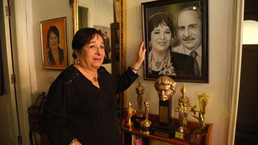 الفنانة سميرة عبدالعزيز في منزلها أمام صورة تجمعها وزوجها الراحل محفوظ عبدالرحمن