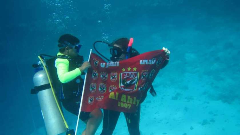 آدم يحمل علم الأهلي تحت الماء