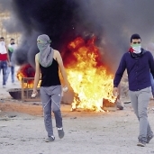 عدد من الشباب الفلسطينيين يحملون الحجارة فى مواجهة قوات الاحتلال الإسرائيلى «أ. ف. ب»