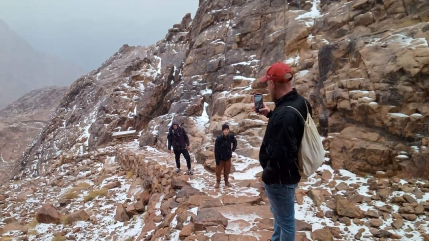 السياح فوق جبل موسي والثلوج حولهم