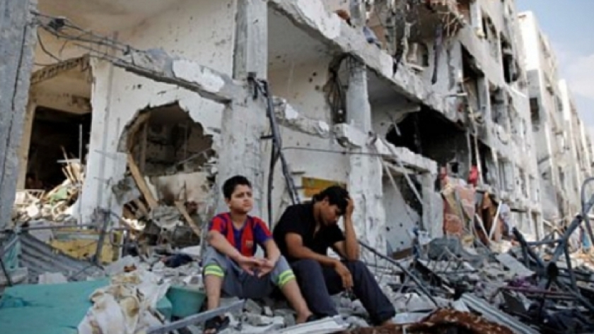 أطفال يجلسون فوق منازلهم المدمرة بغزة