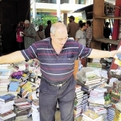 صاحب أحد أكشاك الجرائد يحمل الكتب على الرصيف