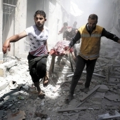 سوريان أثناء نقل ضحايا القصف المتواصل «أ. ف. ب»