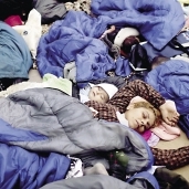 لاجئون سوريون ينامون على الأرض بعد وصولهم إلى اليونان «أ.ف.ب»