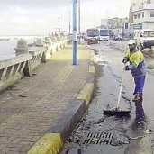 عامل يزيل آثار الأمطار بشوارع الإسكندرية