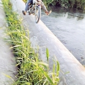 «هاشم» مستقلاً دراجته البخارية فوق ماسورة الصرف