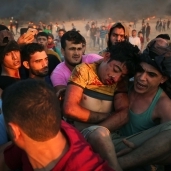 فلسطينيون يحملون مصاباً إثر مواجهات مع الجيش الإسرائيلى على الحدود بين غزة والأراضى المحتلة«أ.ف.ب»