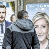 فرنسى ينظر للافتات دعاية مرشحى الرئاسة الفرنسية «أ.ف.ب»