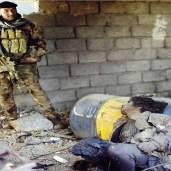 جندى عراقى بجوار جثة لإرهابى من «داعش» «أ.ف.ب»