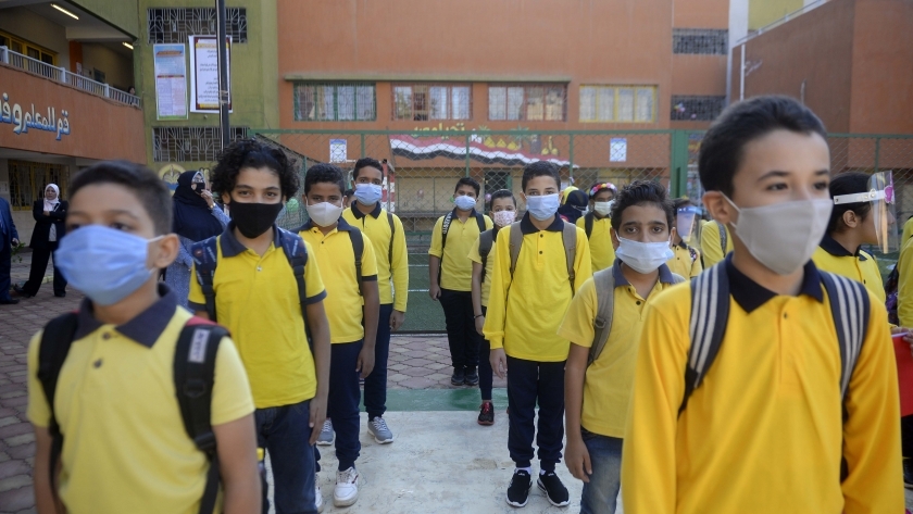 طلاب المدارس يلتزمون بارتداء الكمامات الطبية للوقاية من كورونا في الطابور الصباحي