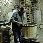«عادل» أثناء تصنيع أحد البراميل داخل الورشة