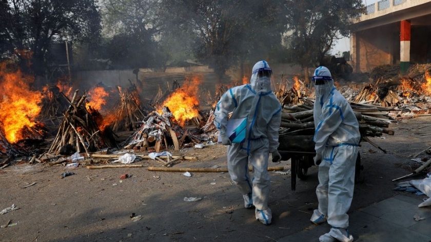 عمال الصحة يرتدون معدات الوقاية ويحملون الخشب لإعداد محرقة لضحايا فيروس كورونا في الهند