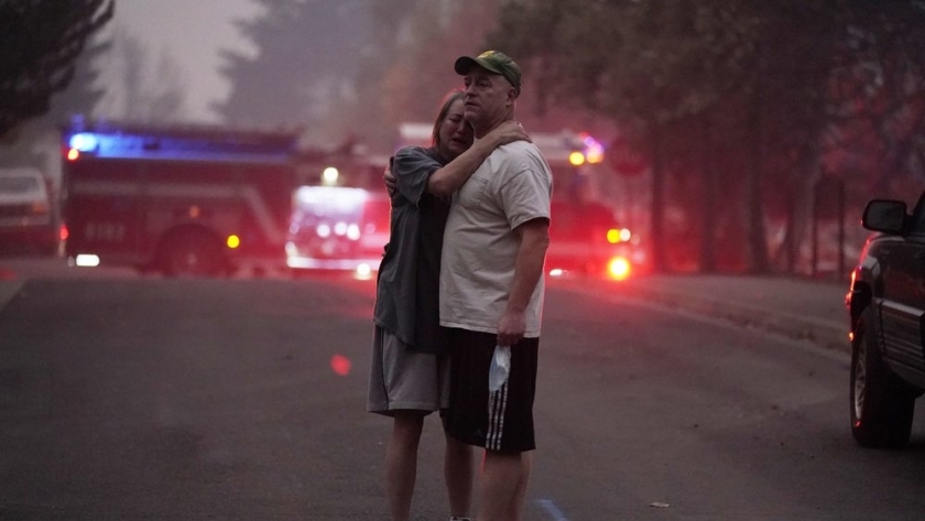 زوجان يحتضنان بعضهما بعد أن دمرت حرائق الغابات منزلهما