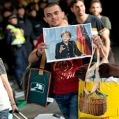 لاجيء سوري يحمل صورة "ميركل"