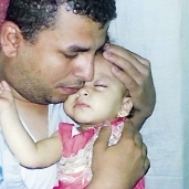 أب يحتضن ابنته المريضة فى انتظار «محلول جفاف آمن»